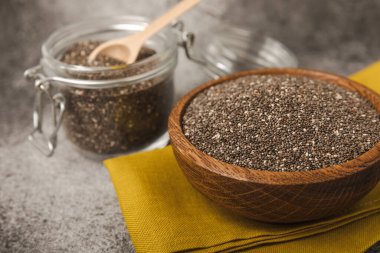 Chia seeds in bowls, spoons and glass jars on a black marble background. SUPERFOOD and antioxidant. Healthy food concept. Gluten free. Copy space.