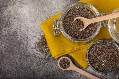 Chia seeds in bowls, spoons and glass jars on a black marble background. SUPERFOOD and antioxidant. Healthy food concept. Gluten free. Copy space.
