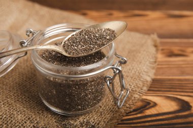 Chia seeds in a small glass jar and a spoon on a brown wood background. SUPERFOOD and antioxidant. Healthy food concept. Gluten free.