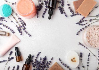 Essential oils, handmade soap, body cream, scrub and lavender flowers on a white textured background. Spa concept. Relaxation and relaxation. Body and skin care. Place for text. Place to copy.
