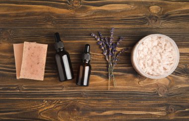Essential oils, serum, scrub, handmade soap and lavender flowers on a brown textural background. Spa concept. Relaxation and relaxation.