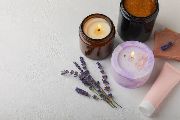 Candles, handmade soap, body cream and lavender flowers on a white textural background. Spa concept. Relaxation and relaxation. Body and skin care. Place for text. Place to copy.