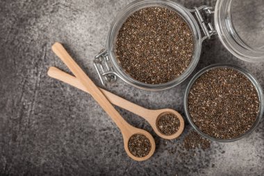 Chia seeds in a bowl and spoons on black marble. Superfood. Antioxidant. Healthy food. Proper nutrition. Diet concept. Place for text. Place to copy.