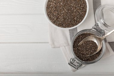 Chia seeds in jar and spoons on white texture wood. Superfood. Antioxidant. Healthy food. Proper nutrition. Diet concept. Place for text. Place to copy. selective focus.