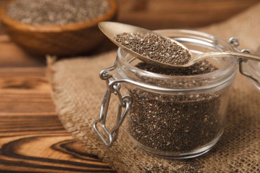 Chia seeds in jar and spoons on brown texture wood. Superfood. Antioxidant. Healthy food. Proper nutrition. Diet concept. Place for text. Place to copy. selective focus.