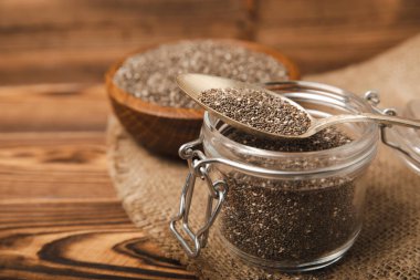 Chia seeds in jar and spoons on brown texture wood. Superfood. Antioxidant. Healthy food. Proper nutrition. Diet concept. Place for text. Place to copy. selective focus.