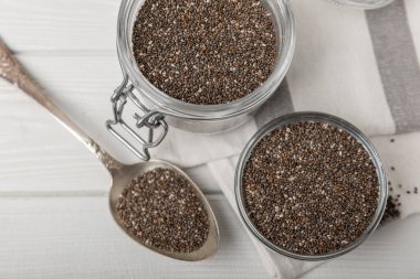 Chia seeds in jar and spoons on white texture wood. Superfood. Antioxidant. Healthy food. Proper nutrition. Diet concept. Place for text. Place to copy. selective focus.
