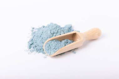 Blue spirulina powder in wooden spoon isolated on white background. Natural vegan superfood. Food supplement. Phycocyanin extract.