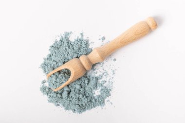 Blue spirulina powder in wooden spoon isolated on white background. Natural vegan superfood. Food supplement. Phycocyanin extract.