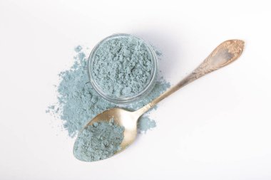 Blue spirulina powder in glass jar and spoon isolated on white background. Natural vegan superfood. Food supplement. Phycocyanin extract.