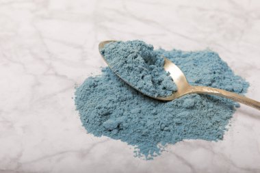 Blue Spirulina algae powder on white marble background. Diet and detox concept.Natural vegan superfood. Food supplement. Copy space. Place for text.