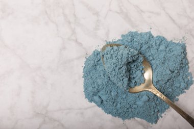 Blue Spirulina algae powder on white marble background. Diet and detox concept.Natural vegan superfood. Food supplement. Copy space. Place for text.