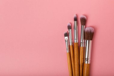 Cosmetic product for makeup. Makeup brushes on a pink background. Creative fashion concept. Collection of cosmetic makeup brushes, top view, banner.Flat lay.