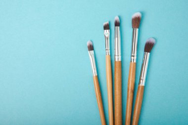 Cosmetic product for makeup. Makeup brushes on a blue background. Creative fashion concept. Collection of cosmetic makeup brushes, top view, banner.Flat lay.