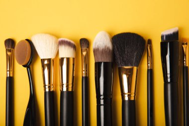 Cosmetic product for makeup. Makeup brushes on a yellow background. Creative fashion concept. Collection of cosmetic makeup brushes, top view, banner.Flat lay.