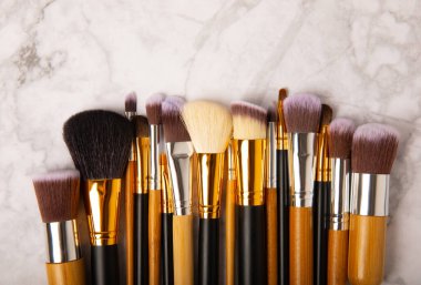 Cosmetic product for makeup. Makeup brushes on a white marble background. Creative fashion concept. Collection of cosmetic makeup brushes, top view, banner.Flat lay.