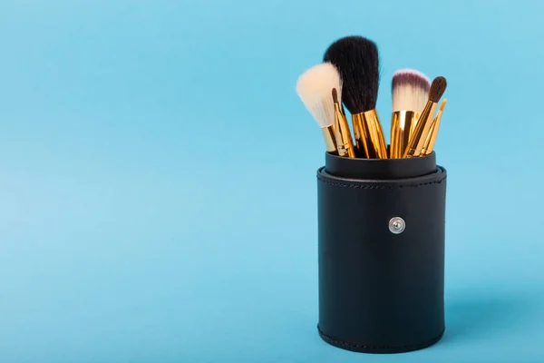 Cosmetic product for makeup. Makeup brushes on a blue background. Creative fashion concept. Collection of cosmetic makeup brushes, top view, banner.Flat lay.