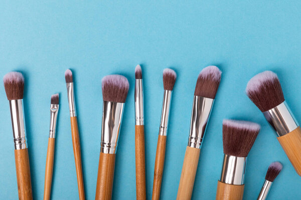 Cosmetic product for makeup. Makeup brushes on a blue background. Creative fashion concept. Collection of cosmetic makeup brushes, top view, banner.Flat lay.