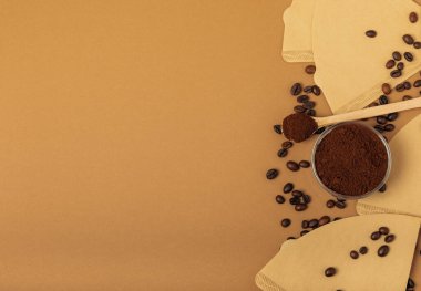 Coffee filter with ground powder on a brown background. fragrant coffee beans for an energizing and invigorating drink. Hand Drip Coffee, Flat Lay of Manual Brew Coffee Tools.