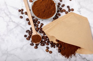 Coffee filter with ground powder on a white marble background. fragrant coffee beans for an energizing and invigorating drink. Hand Drip Coffee, Flat Lay of Manual Brew Coffee Tools
