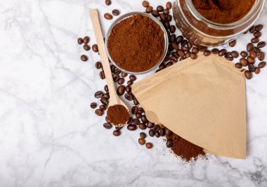 Coffee filter with ground powder on a white marble background. fragrant coffee beans for an energizing and invigorating drink. Hand Drip Coffee, Flat Lay of Manual Brew Coffee Tools