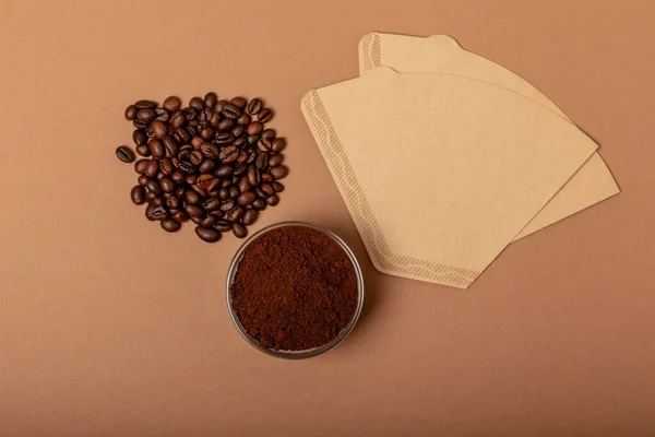 Coffee filter with ground powder on a brown background. fragrant coffee beans for an energizing and invigorating drink. Hand Drip Coffee, Flat Lay of Manual Brew Coffee Tools.