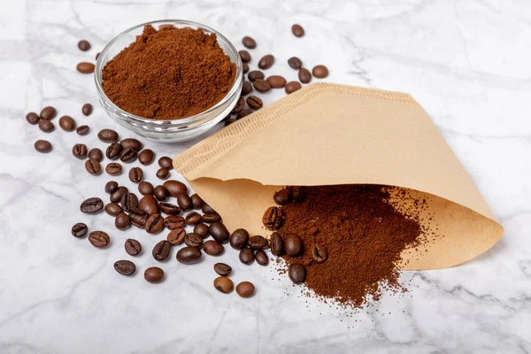 Coffee filter with ground powder on a white marble background. fragrant coffee beans for an energizing and invigorating drink. Hand Drip Coffee, Flat Lay of Manual Brew Coffee Tools