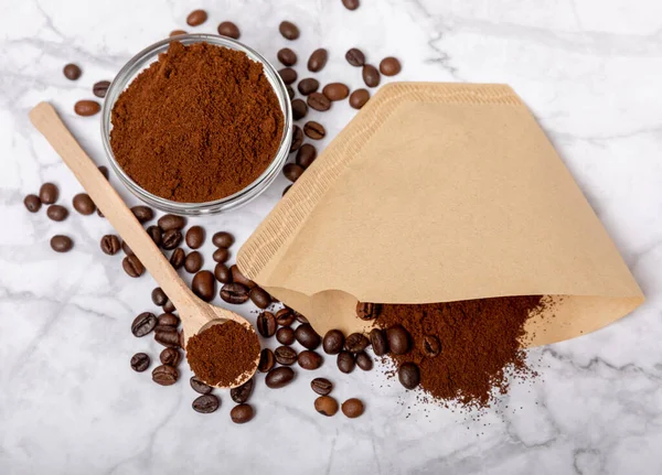 Coffee filter with ground powder on a white marble background. fragrant coffee beans for an energizing and invigorating drink. Hand Drip Coffee, Flat Lay of Manual Brew Coffee Tools