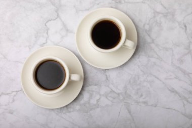 A cup of coffee on a white marble kitchen table. Hot invigorating aroma espresso drink. Place for text. Place to copy. Morning drink.