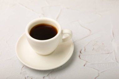 A cup of coffee on a white marble kitchen table. Hot invigorating aroma espresso drink. Place for text. Place to copy. Morning drink.