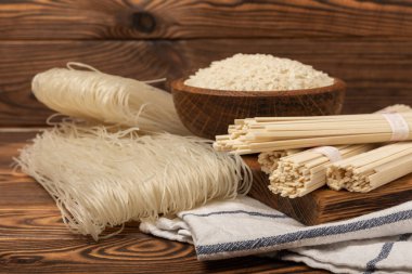 Rice noodles.Rice and noodles with rice flour in a wooden plate on a brown wooden background.Close-up. Place for text. Copy space.