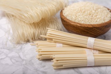Rice noodles.Rice and noodles with rice flour in a wooden plate on a white marble background.Close-up. Useful and healthy food.Place for text. Copy space.