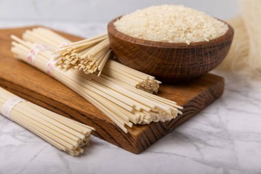 Rice noodles.Rice and noodles with rice flour in a wooden plate on a white marble background.Close-up. Useful and healthy food.Place for text. Copy space.