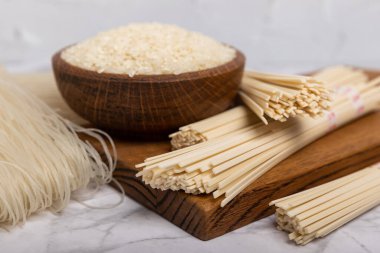 Rice noodles.Rice and noodles with rice flour in a wooden plate on a white marble background.Close-up. Useful and healthy food.Place for text. Copy space.