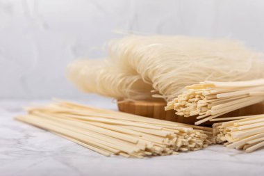 Rice noodles.Noodles with rice flour in a wooden plate on a white marble background.Close-up. Place for text. Copy space.