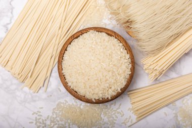 Rice noodles.Rice and noodles with rice flour in a wooden plate on a white marble background.Close-up. Useful and healthy food.Place for text. Copy space.