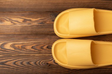 Rubber summer slippers. Replacement shoes for home or office. Yellow slippers on a background of brown space. Relax concepts. Space for text.Space for copy.