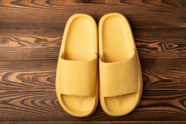 Rubber summer slippers. Replacement shoes for home or office. Yellow slippers on a background of brown space. Relax concepts. Space for text.Space for copy.