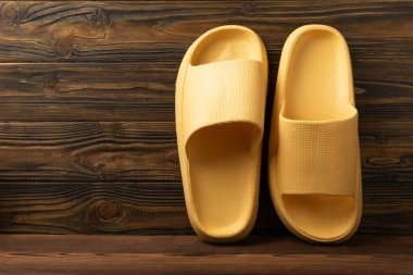 Rubber summer slippers. Replacement shoes for home or office. Yellow slippers on a background of brown space. Relax concepts. Space for text.Space for copy.