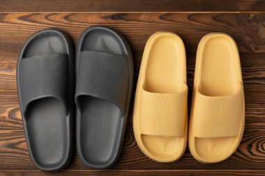 Rubber summer slippers. Replacement shoes for home or office. Yellow slippers on a background of brown space. Relax concepts. Space for text.Space for copy.