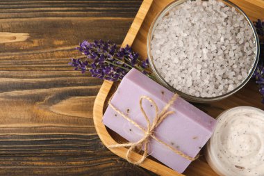 Lavender spa.Cosmetic products sea salt,body cream,handmade soap,scrub,essential oils and lavender flowers on brown wood.Natural herb cosmetic with lavender flowers. Beauty concept. copy space