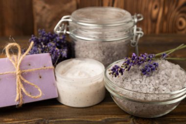 Lavender spa.Cosmetic products sea salt,body cream,handmade soap,scrub,essential oils and lavender flowers on brown wood.Natural herb cosmetic with lavender flowers. Beauty concept. copy space
