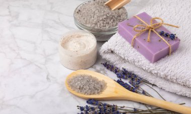 Lavender spa. Cosmetic products sea salt, body cream, scrub, essential oils and lavender flowers on a marble background.Natural herb cosmetic with lavender flowers. Beauty concept. Copy space.