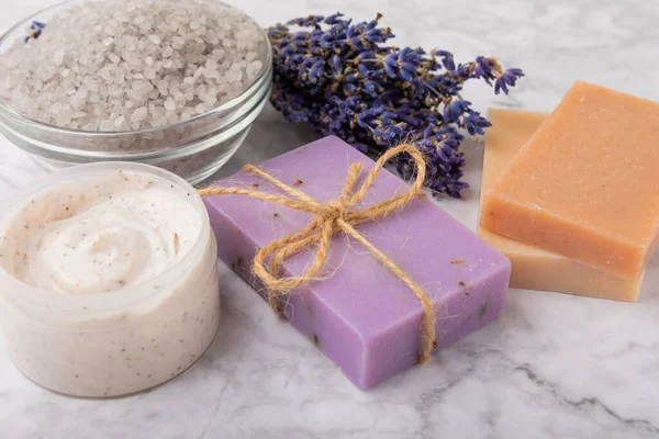 Lavender spa. Cosmetic products sea salt, body cream, scrub, essential oils and lavender flowers on a marble background.Natural herb cosmetic with lavender flowers. Beauty concept. Copy space.