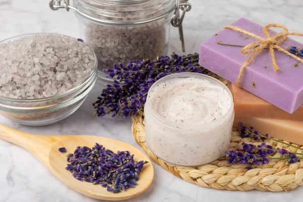 Lavender spa. Cosmetic products sea salt, body cream, scrub, essential oils and lavender flowers on a marble background.Natural herb cosmetic with lavender flowers. Beauty concept. Copy space.