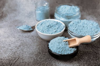Blue spirulina powder in bowls and spoon on black marble background. Natural vegan superfood. food supplement. place for text. Copy space.