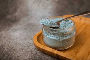 Blue spirulina powder in bowls and spoon on black marble background. Natural vegan superfood. food supplement. place for text. Copy space.