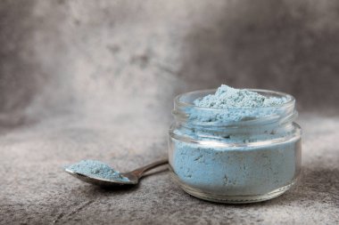 Blue spirulina powder in bowls and spoon on black marble background. Natural vegan superfood. food supplement. place for text. Copy space.