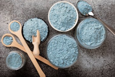 Blue spirulina powder in bowls and spoon on black marble background. Natural vegan superfood. food supplement. place for text. Copy space.