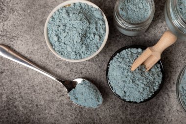 Blue spirulina powder in bowls and spoon on black marble background. Natural vegan superfood. food supplement. place for text. Copy space.